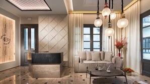 Una moderna hall d'albergo con una reception, un divano, un tavolino da caffè e un lampadario.