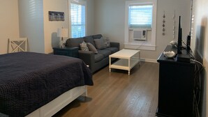 A bedroom with a bed, a nightstand, a dresser, a ceiling fan, and two windows with blinds.