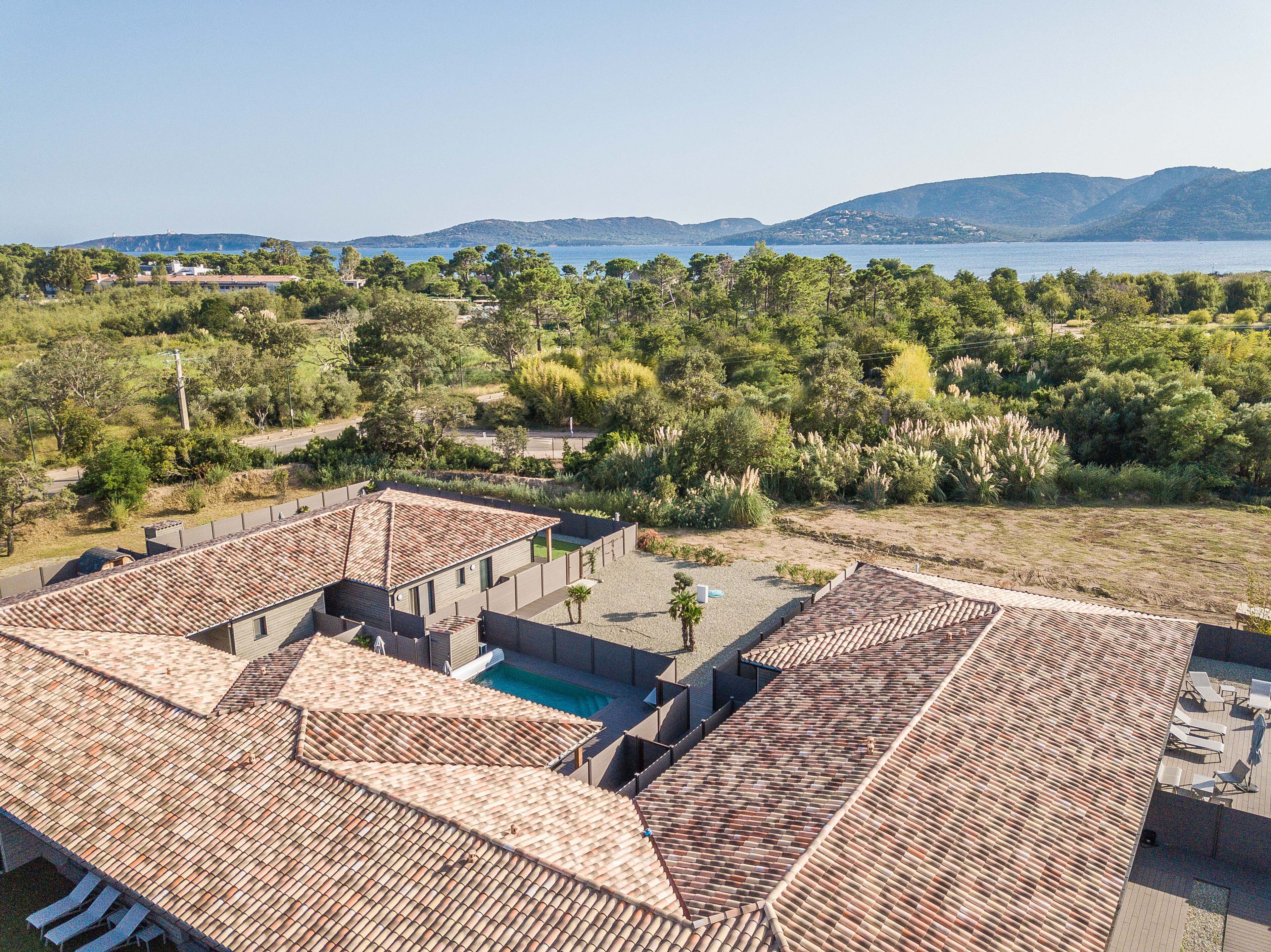 Una villa con techos de tejas de arcilla, piscina y vistas al mar y colinas.