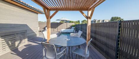 A wooden deck with a pergola overhead, a pool, and a fenced area.