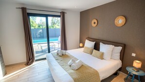 Una camera da letto con un letto, un tavolino, una lampada e vista su una piscina.