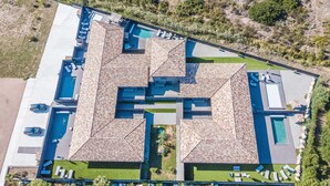 Vista aerea di un resort moderno con diverse piscine, aree salotto all'aperto e un paesaggio curato.