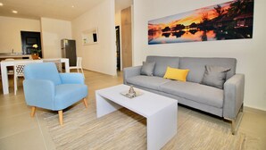 Un salon moderne avec un canapé gris, un fauteuil bleu et une table basse blanche.
