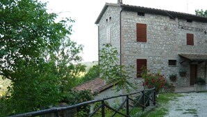 A stone building with a rustic appearance, featuring a gravel path and a wooden fence. - Casale Luigina (Monte Castello di Vibio)