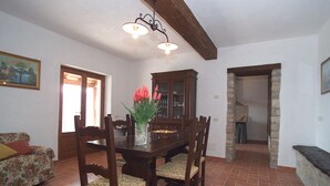 A dining area with a wooden table, chairs, and a vase with flowers. - Casale Luigina (Monte Castello di Vibio)