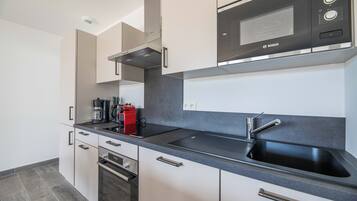 A modern kitchen with a Bosch microwave, a coffee maker, and a sink.