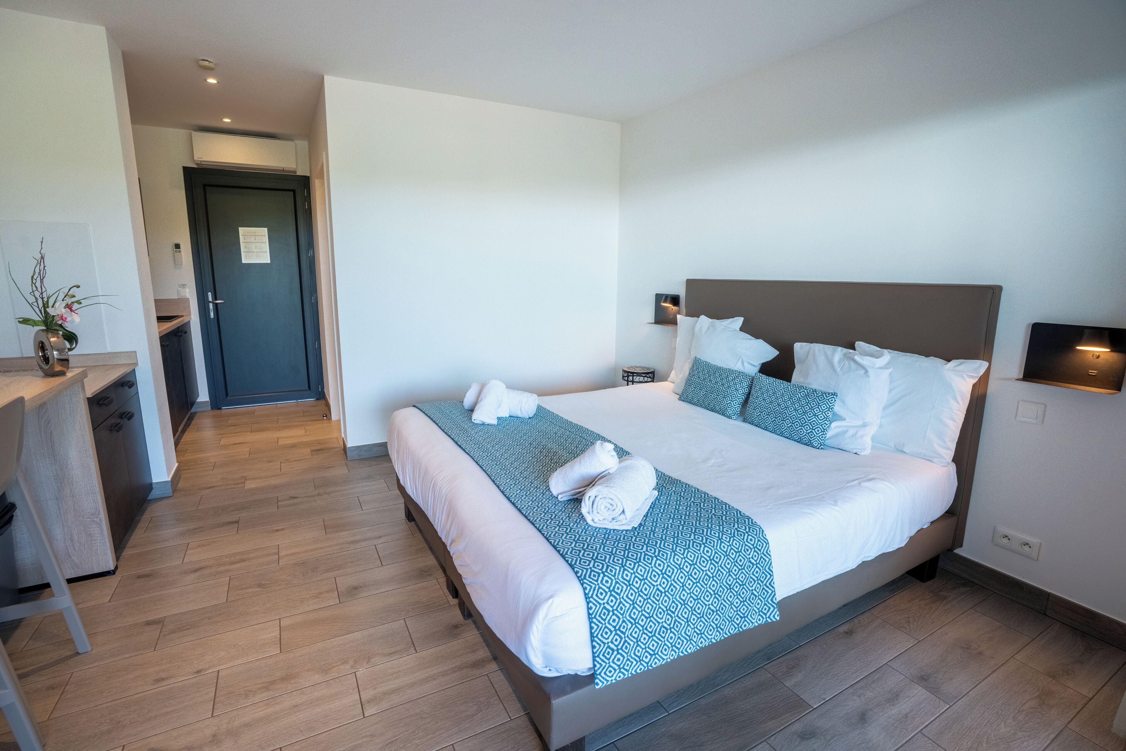 A hotel room with a bed, bedside table, and a desk area.