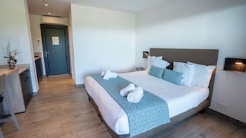 A hotel room with a bed, bedside table, and a desk area.