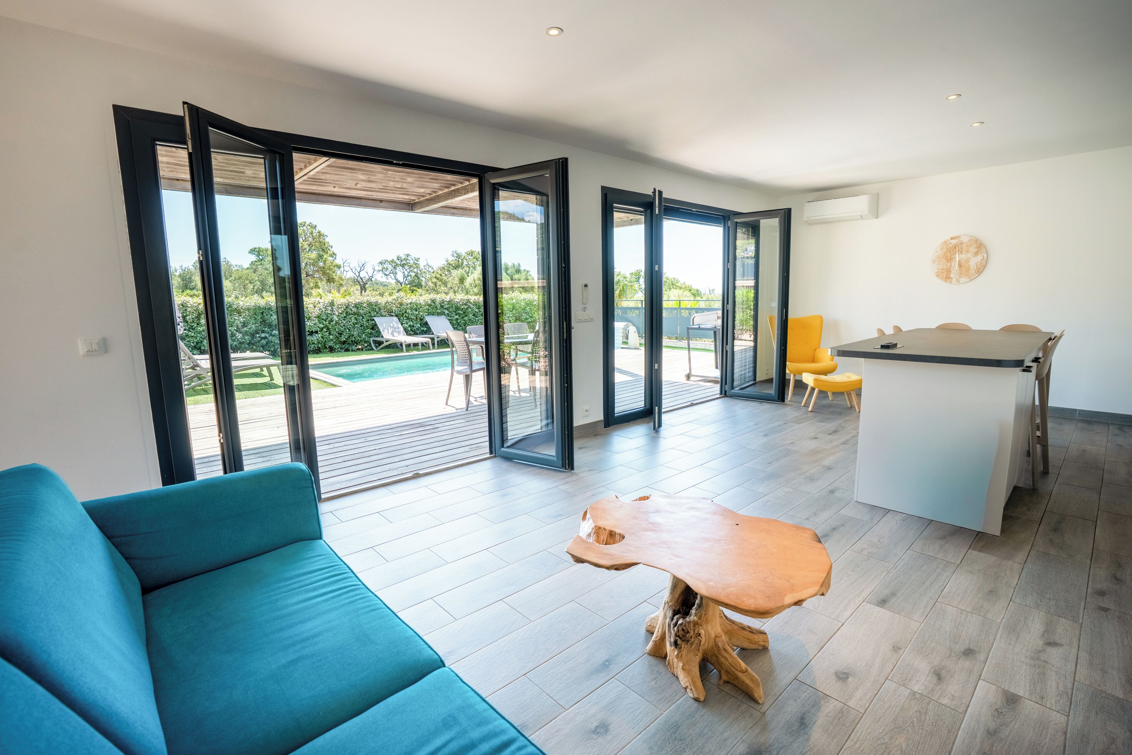 A modern living room with a sofa, a wooden coffee table, and a dining area with a table and chairs.
