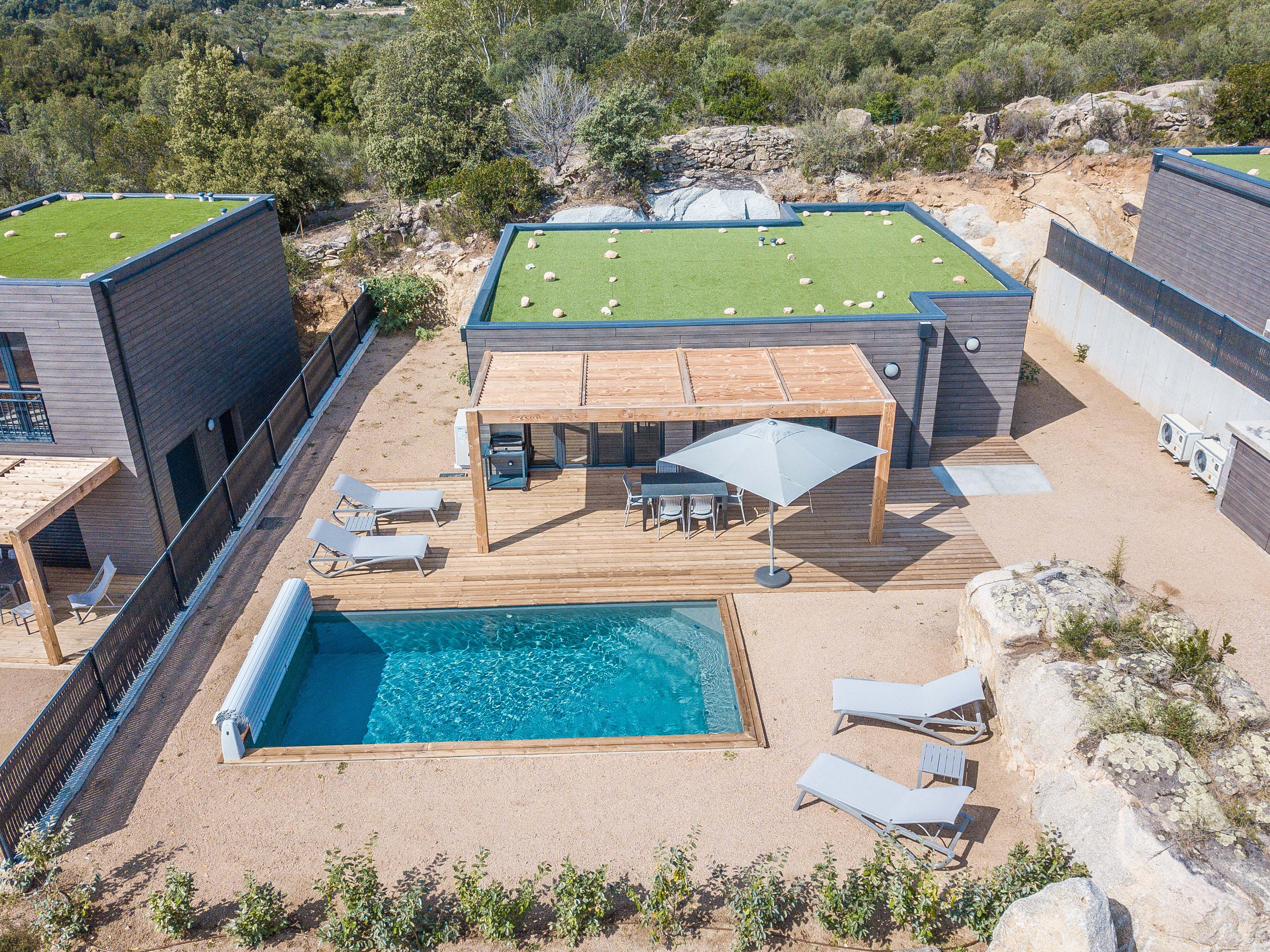Zona piscina sul tetto con terrazza in legno, lettini e angolo relax coperto.