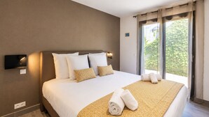 Ein Hotelzimmer mit einem großen Bett, einem an der Wand montierten Thermostat und einem Fenster mit Vorhängen.