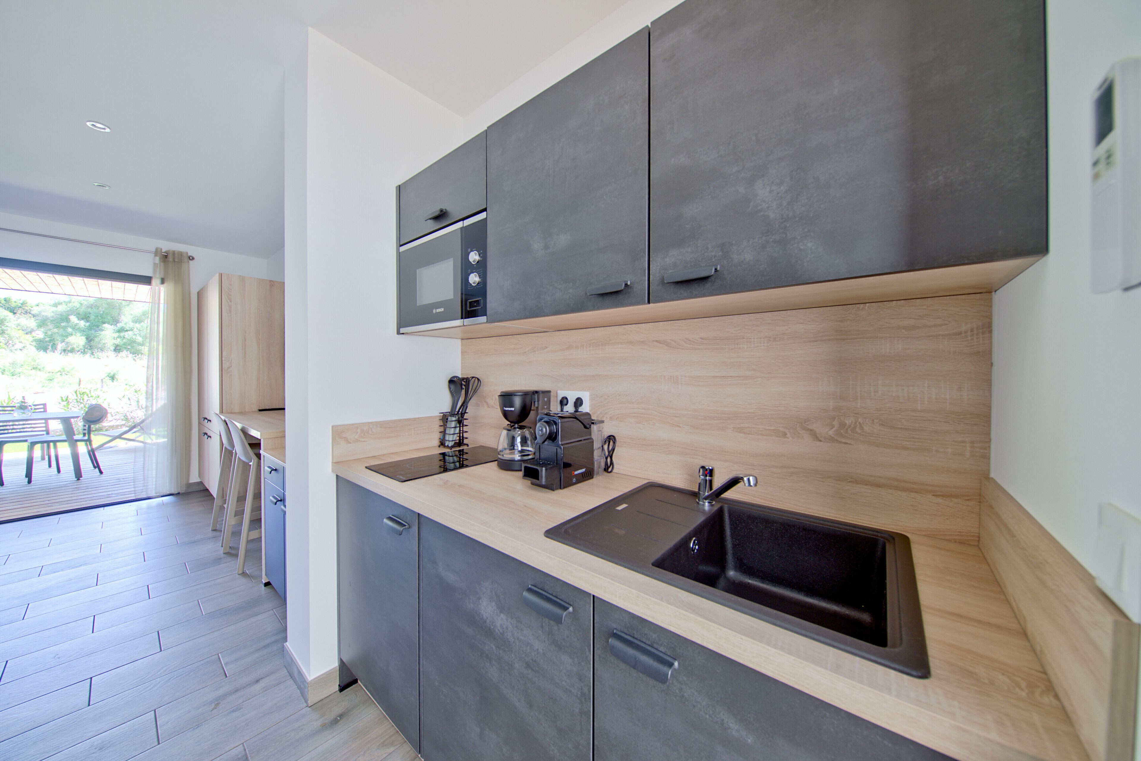 A modern kitchen with dark cabinets, a wooden countertop, and a built-in microwave.