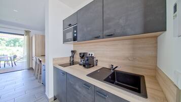 A modern kitchen with dark cabinets, a wooden countertop, and a built-in microwave.