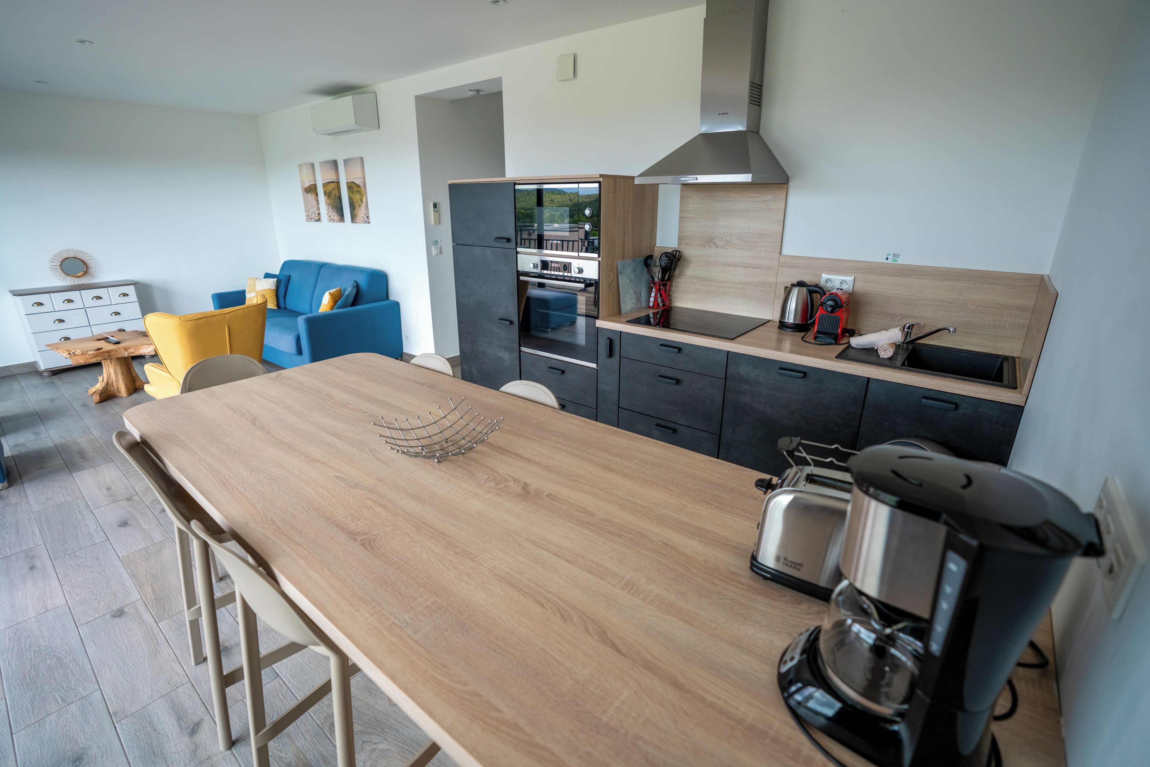 A modern kitchen with a wooden countertop, a coffee maker, and a built-in oven.