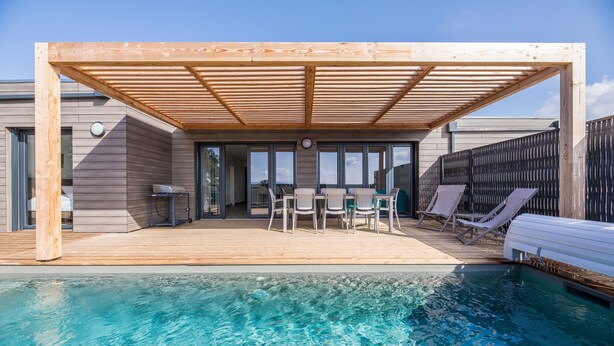 Ein Poolbereich mit Holzterrasse, Liegestühlen und einem Tisch.