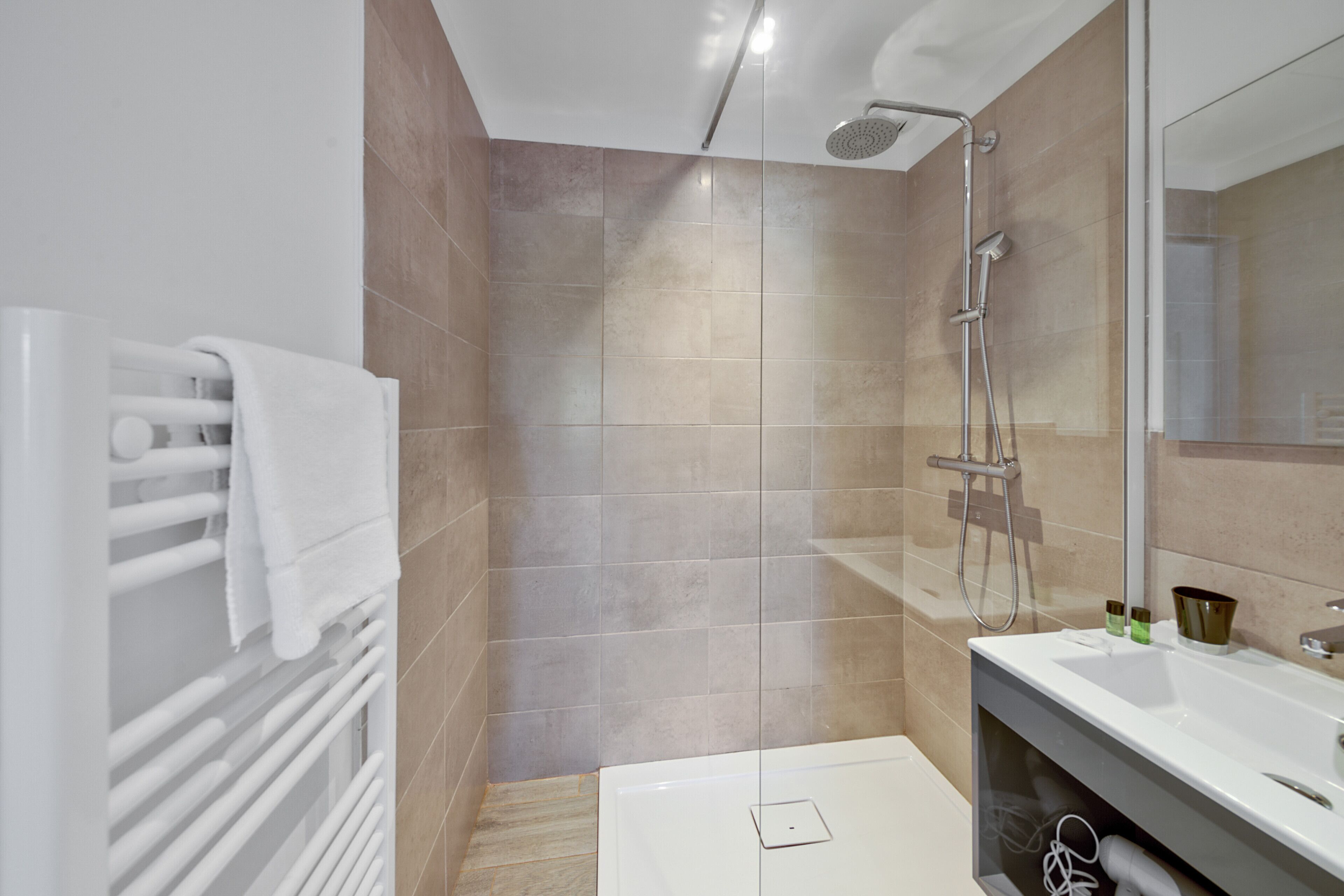 Un baño moderno con cabina de ducha de vidrio, una bañera blanca y un espejo grande sobre el lavabo.