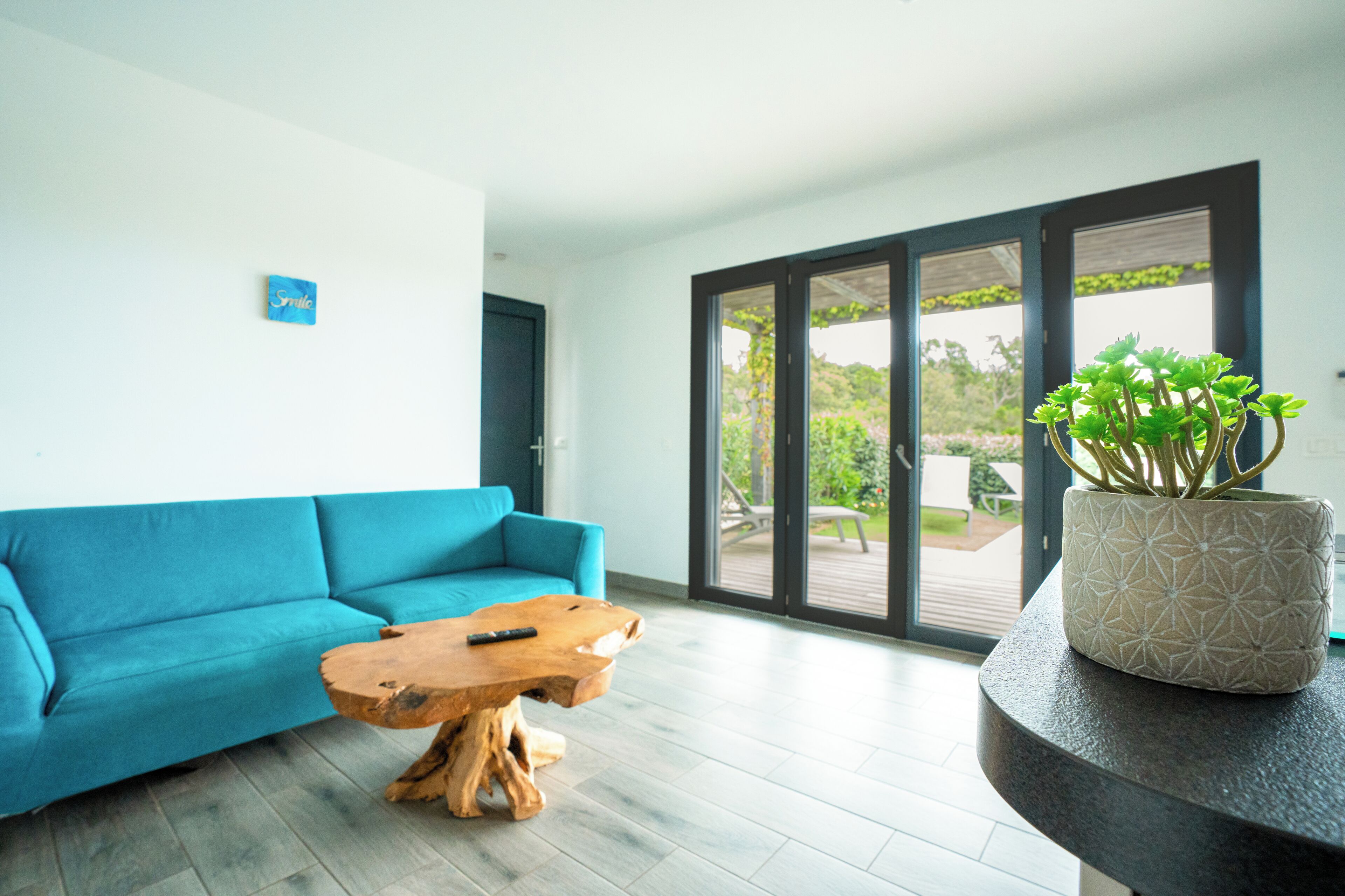 A modern living room with a blue sofa, a wooden coffee table, and a potted plant on a curved console table.
