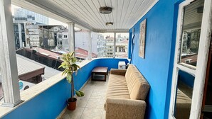 A balcony with a beige sofa, a potted plant, and a view of surrounding buildings. - Beyaz Suites & Hotel (Istanbul)