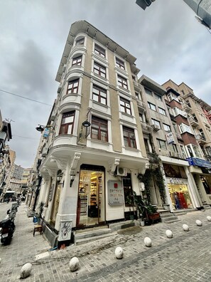 A multi-story building with a prominent entrance, a sign for 'ERTEKS Group Tentsim A.S.', and a storefront named 'ERVA'. - Beyaz Suites & Hotel (Istanbul)