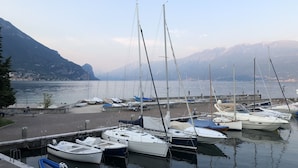 A marina with several boats docked, a small dock area, and a mountainous backdrop. - Gorgeous 9-seater villa, perfect for families with large garden by the lake (Bogliaco)