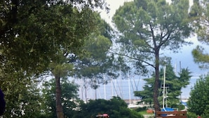 An outdoor dining setup with a table set for four, overlooking a body of water with boats in the background. - Gorgeous 9-seater villa, perfect for families with large garden by the lake (Bogliaco)