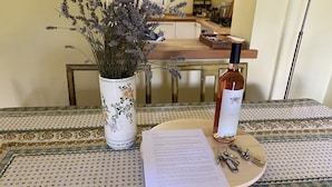 A dining table with a floral-patterned tablecloth, a vase with dried flowers, a bottle of Chianti wine, a menu, and a set of keys. - Gorgeous 9-seater villa, perfect for families with large garden by the lake (Bogliaco)