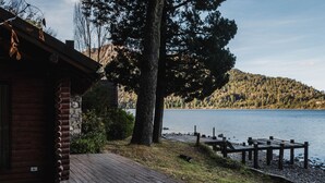 A wooden cabin with a dock extending into a lake, surrounded by trees and hills. - Beatiful Cabin in Bariloche (San Carlos de Bariloche)