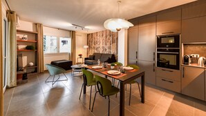 Una cocina moderna con comedor, que incluye horno empotrado, cafetera y mesa para cuatro.