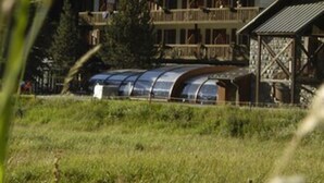 A large wooden building with multiple balconies, surrounded by lush green hills. - Le Fontenil (Abriès-Ristolas)