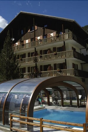 A hotel with a pool area, multiple balconies, and a wooden deck. - Le Fontenil (Abriès-Ristolas)