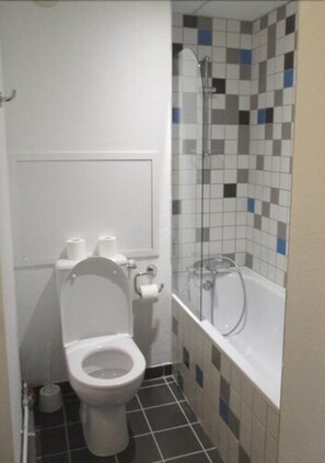 A small bathroom with a toilet, a shower, and a tiled wall. - Le Fontenil (Abriès-Ristolas)