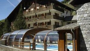 A multi-story building with a balcony, a swimming pool, and a glass-enclosed structure. - Le Fontenil (Abriès-Ristolas)