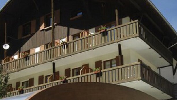 A pool area with a wooden deck and a covered section. - Le Fontenil (Abriès-Ristolas)