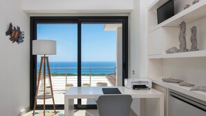 Eine moderne Küche mit Meerblick, ein Essbereich mit Tisch und Stühlen sowie ein Regal mit Dekoration.