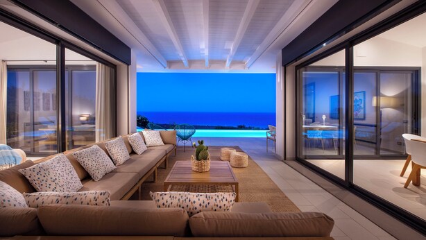 Ein modernes Wohnzimmer mit einer großen Couch, einem Couchtisch und Blick auf den Ozean.