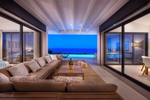 Un salon moderne avec un grand canapé, une table basse et une vue sur l’océan.