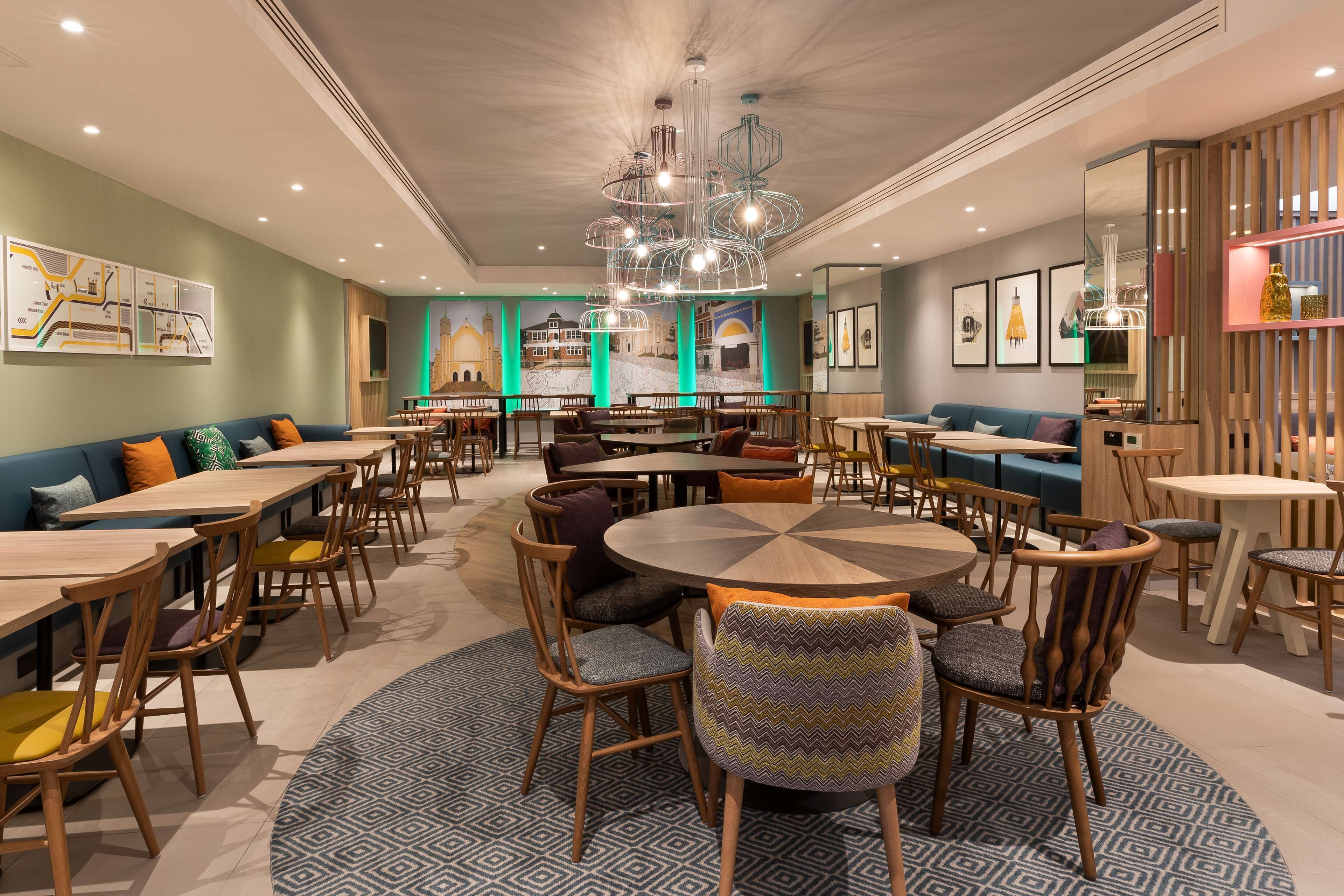 Un restaurante moderno con mesas redondas, sillas de madera y una lámpara central.