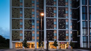 A modern hotel with a distinctive geometric facade, multiple entry points, and a visible brand name. - Hampton by Hilton London Ealing (London)
