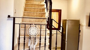 A staircase with a dreamcatcher decoration, a refrigerator, and a wooden door in a residential setting. - Fantastico Budoni Tauanella ARGO01 (Budoni)