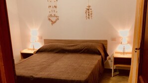 A bedroom with a bed, two bedside tables, and wall-mounted lamps. - Fantastico Budoni Tauanella ARGO01 (Budoni)