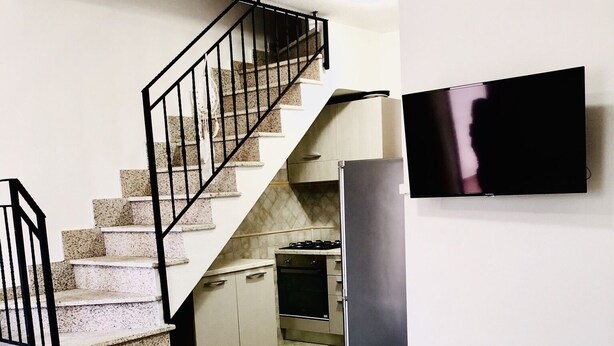 A compact kitchen with a refrigerator, stove, and microwave. A staircase leads to a second floor. - Fantastico Budoni Tauanella ARGO01 (Budoni)