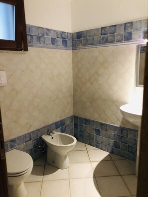Un baño con inodoro, bidé y lavamanos.