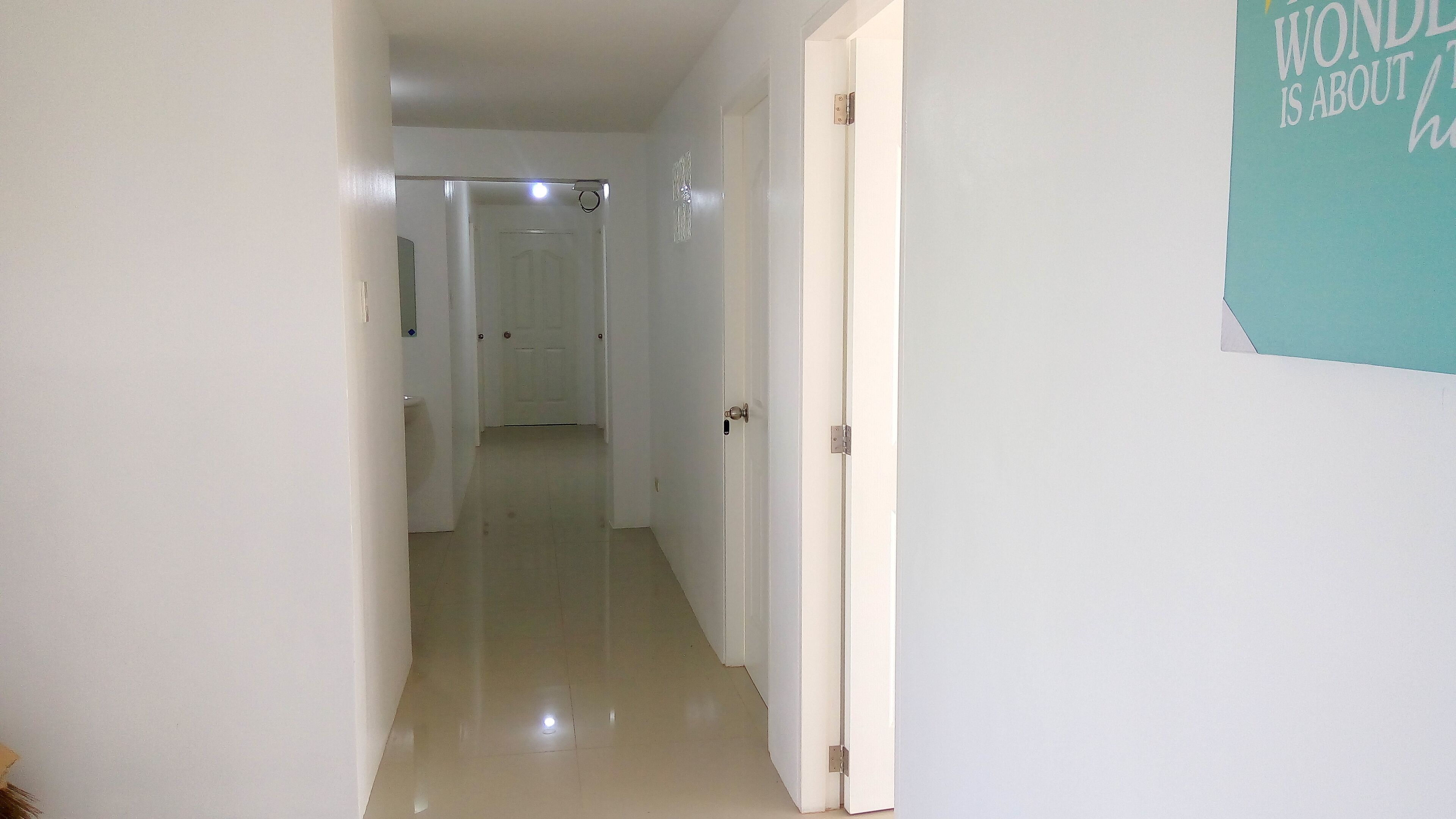 A hallway with white walls and a door on the right.