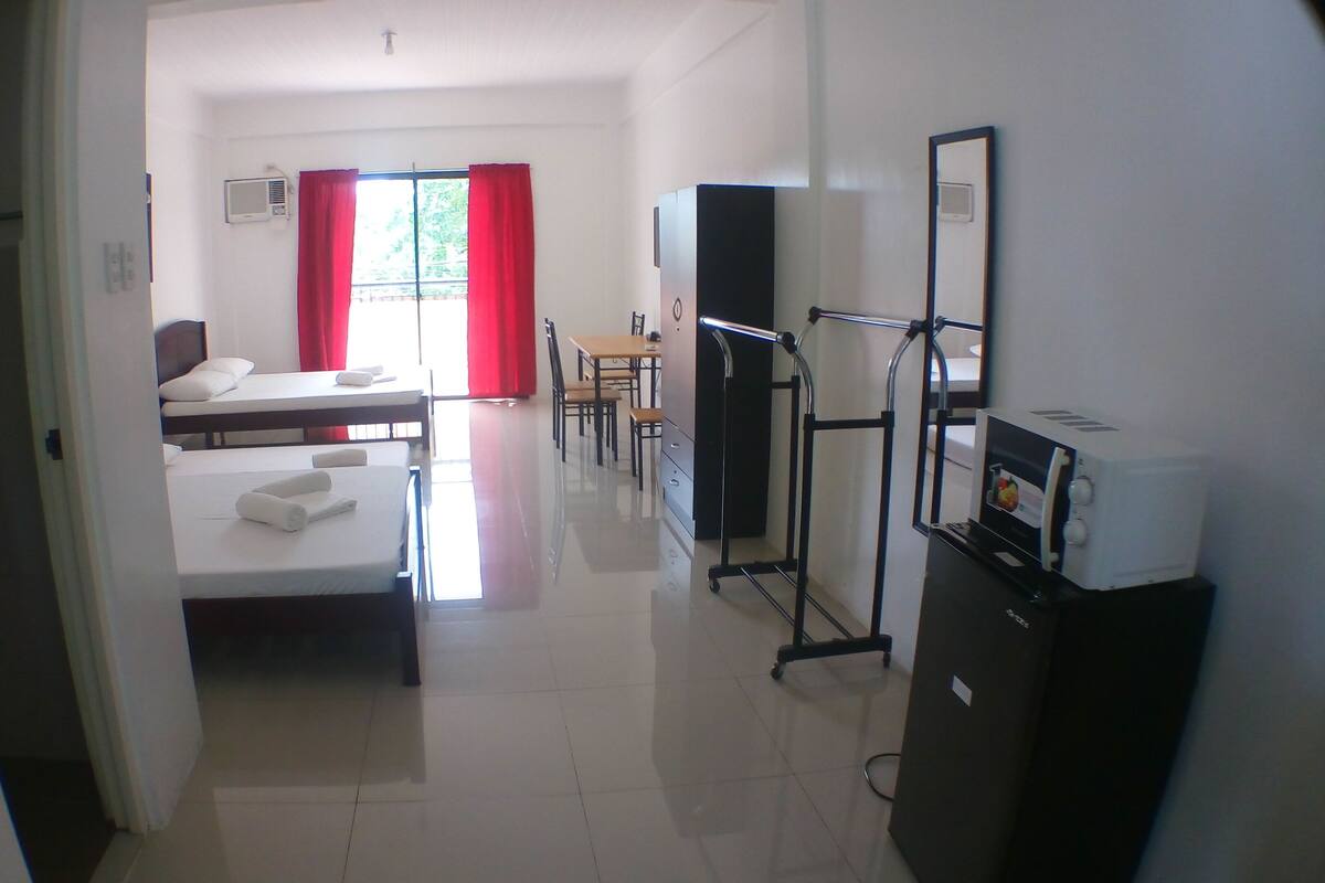 A hotel room with a bed, a desk, a chair, a TV, and a wardrobe.