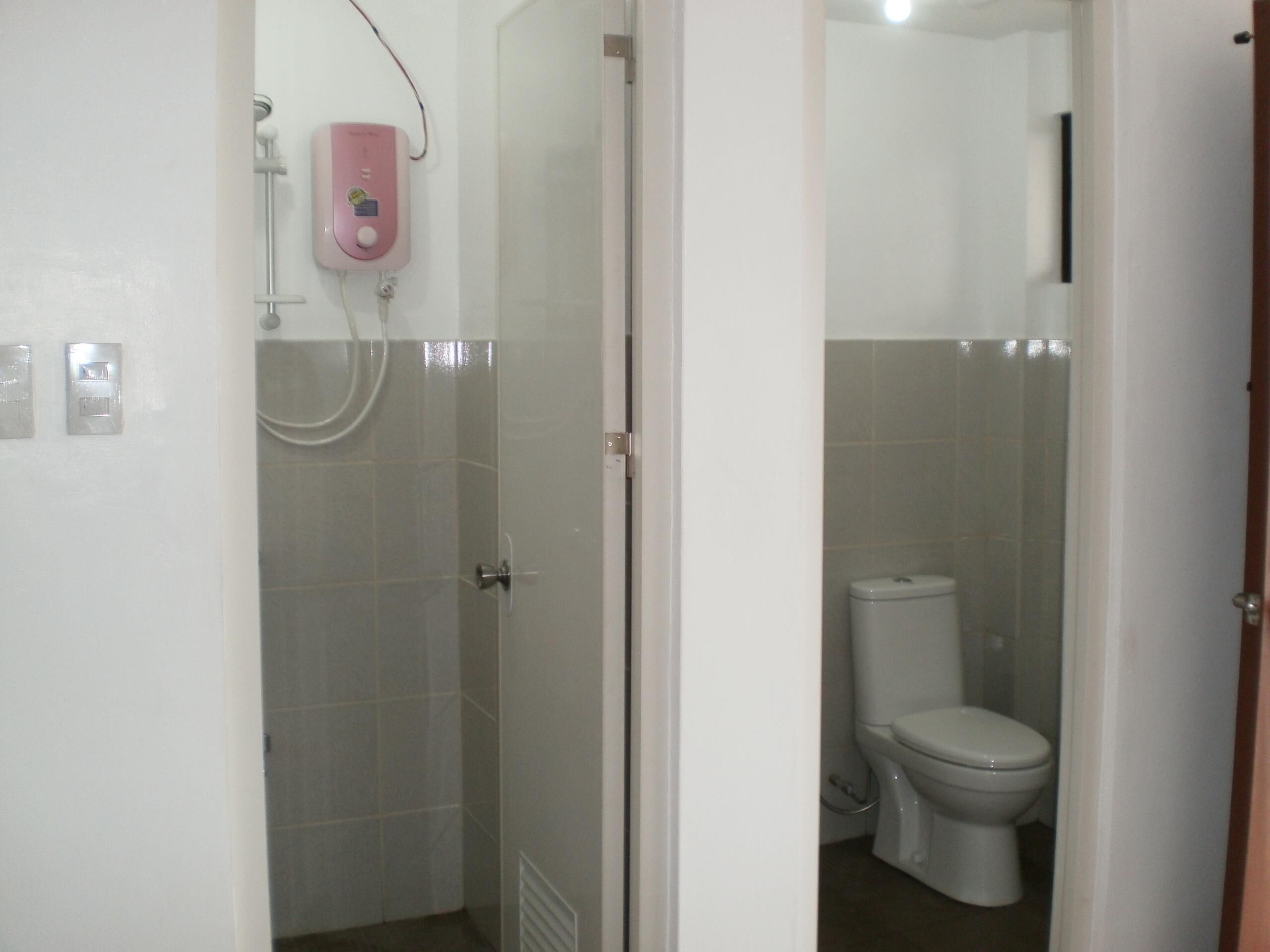 Et badeværelse med bruser, toilet og håndtørrer.