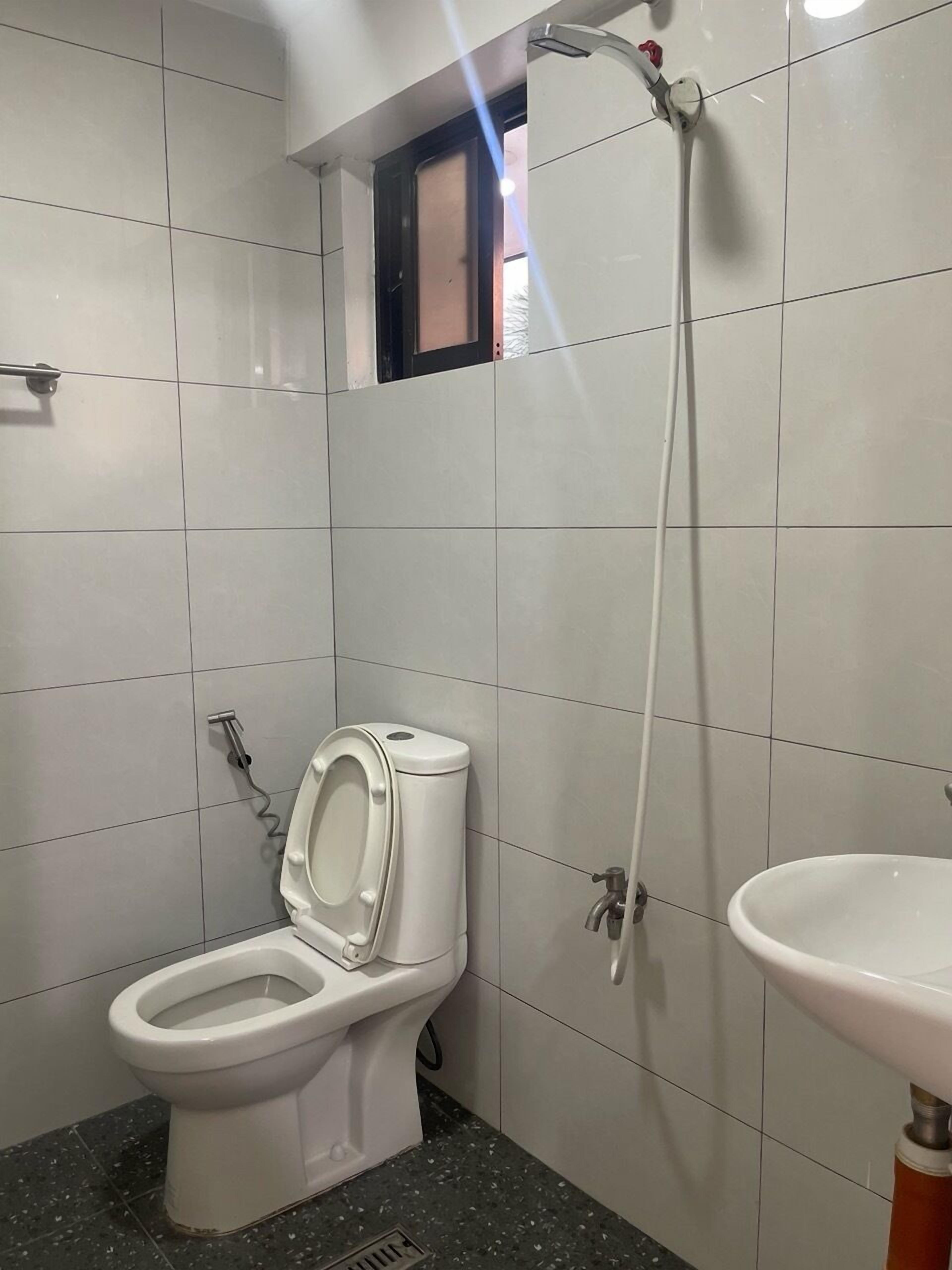 A bathroom with a toilet, a shower, and a sink.