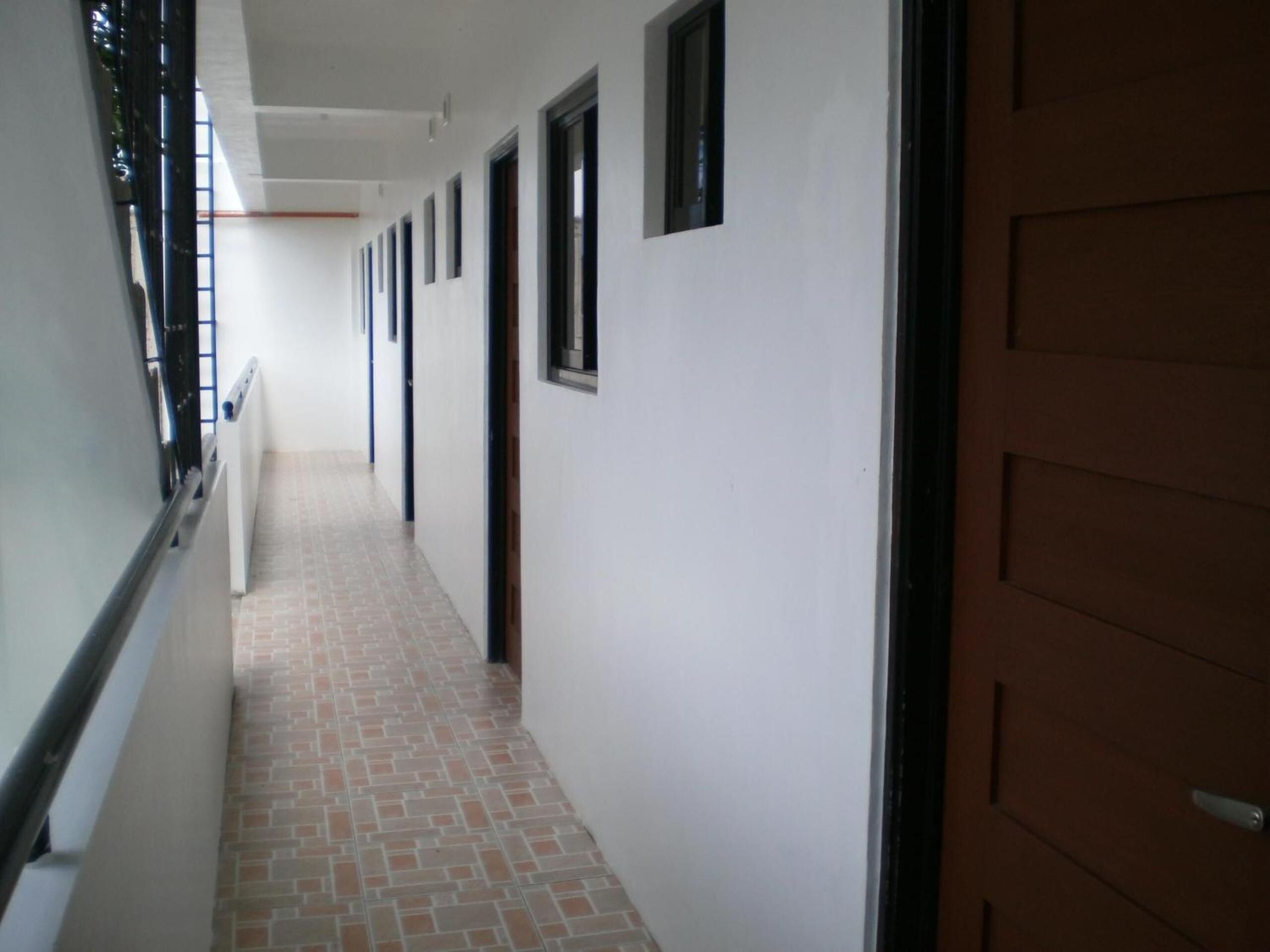 A long, narrow hallway with a tiled floor and a series of doors on one side.