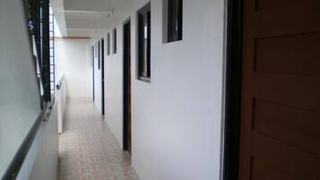 A long, narrow hallway with a tiled floor and a series of doors on one side.