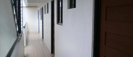 A long, narrow hallway with a tiled floor and a series of doors on one side.