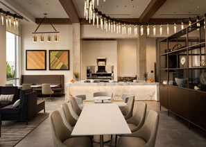 A modern kitchen with a marble countertop, a built-in oven, and a dining area with a white table and cushioned chairs. - Canopy by Hilton Dallas Frisco Station, TX (Frisco)